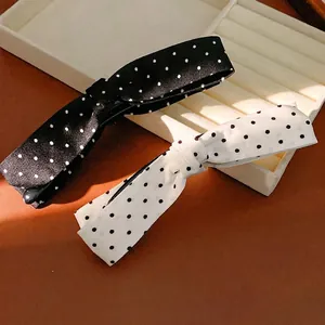 Elegant black and white polka dot fabric bow hair clips on jewelry tray