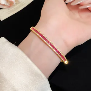 Detailed macro view of vintage gold bangle featuring red stones and clear zircon accents
