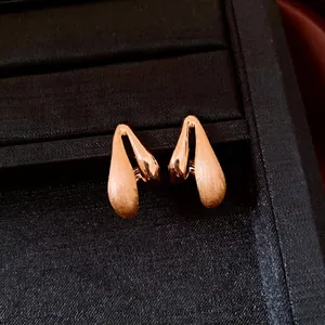 Elegant 18k gold-plated teardrop earrings with brushed and polished finish on black tray