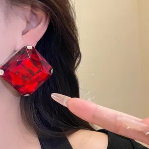 Detailed view of elegant red square diamond-cut gemstone earrings on model's ear