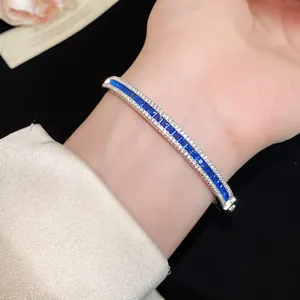 Detailed macro view of a luxury silver bangle featuring a row of brilliant blue square zircons