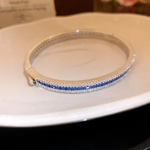 Detail view of a retro style silver bangle with blue cubic zirconia inlay.