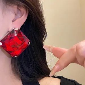 Detailed close-up showing a large red faceted crystal rhombic stud earring on a model ear