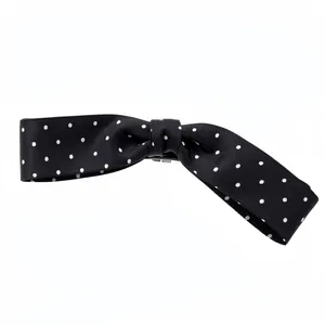 Elegant black fabric bow hair clip featuring classic white polka dots and secure clip
