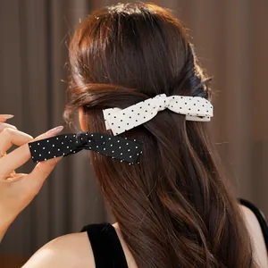 Detailed view of elegant black and white polka dot bow hair clips on wavy brown hair