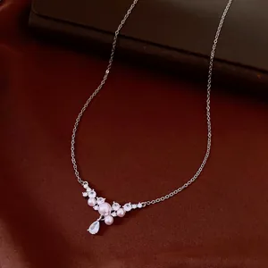 Close-up of elegant necklace featuring soft pink pearls and a sparkling crystal drop pendant.