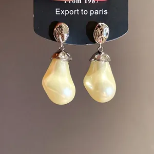 Retro silver drop earrings with irregular cream pearl pendants and wrinkled metal caps.