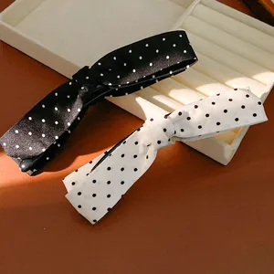 Close-up detail of elegant black and white polka dot fabric bow hair clips for women