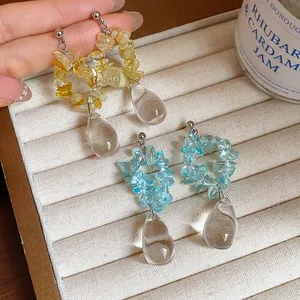 Gros plan d'élégantes boucles d'oreilles gouttes d'eau en résine irrégulière, jaune et bleu.