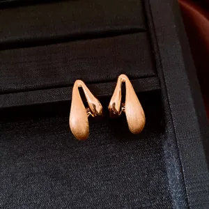 Detailed view of gold-plated teardrop earrings with elegant brushed finish.