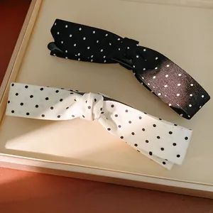 Close-up of black and white polka dot fabric bow hair clips on a display tray