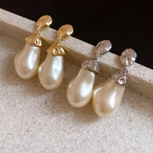 Close-up of baroque pearl drop earrings with elegant crumpled gold and silver metal textures