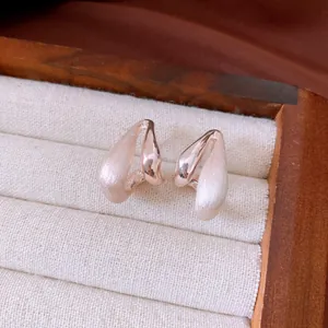 Close-up of 18k gold plated water drop earrings featuring brushed and polished textures