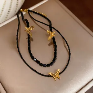 Close-up view of black beaded double-layer necklace featuring golden butterfly pendants