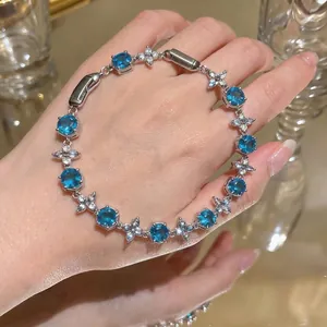 Elegant silver-toned bracelet featuring blue zircons and delicate flower clusters on hand