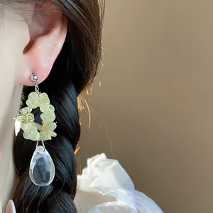 Vue rapprochée d'élégantes boucles d'oreilles en résine jaune et goutte d'eau sur l'oreille