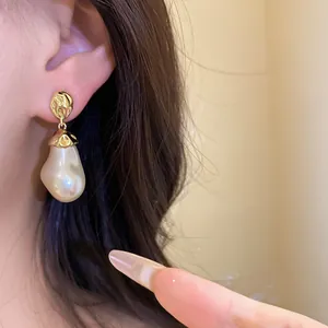 Detail of vintage baroque pearl pendant earring with golden crumpled metal stud