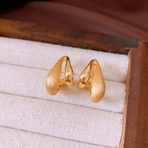Close-up of elegant brushed and polished 18k gold-plated drop stud earrings