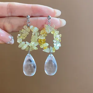 Gros plan de boucles d'oreilles en résine jaune irrégulière et gouttes d'eau claires
