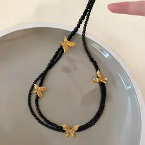 Close-up of French vintage multi-layered beaded necklace with gold butterfly charms