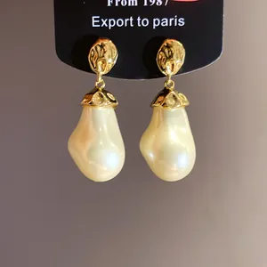 Detailed macro view of gold hammered texture baroque pearl drop earrings