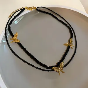 Detailed macro view of the retro layered black beaded necklace with golden butterfly pendants.