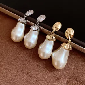Detail showing pleated metal textures and irregular baroque pearl drops in gold and silver.