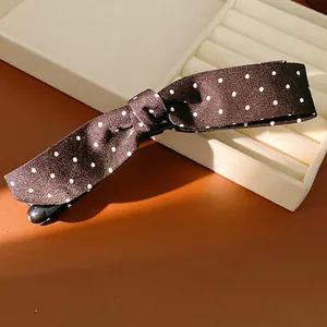 Detail view of black fabric polka dot bow hair clip on jewelry box display tray.