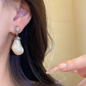 Close-up detail of vintage baroque pearl drop earrings with textured silver metal disc