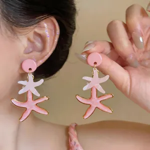 Primer plano detallado de pendientes de estrella de mar de resina rosa con diseño capas