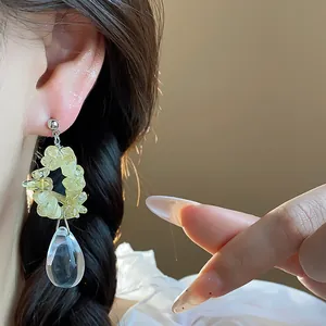 Gros plan détaillé d'élégantes boucles d'oreilles gouttes en résine jaune sur un modèle