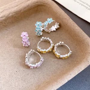Detailed close-up view of colorful enamel flower hoop earrings in pink, blue, and yellow.