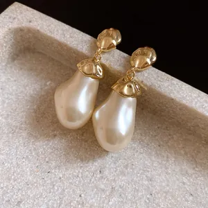 Close-up detail showing the baroque pearl drop and textured gold metal of these earrings