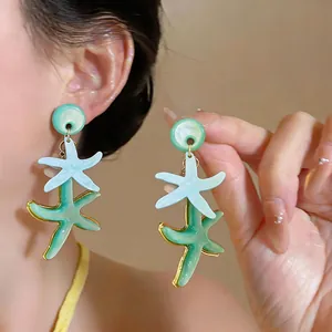 Primer plano de elegantes pendientes de estrella de mar en resina para vacaciones