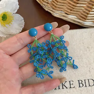 Close-up of summer holiday style blue and green beaded tassel floral earrings