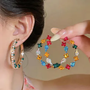 Detail view of vibrant square and teardrop zirconia stones on gold hoop earrings