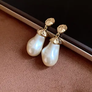 Macro view showing the baroque pearl drop earrings with textured gold metal accents