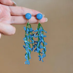 Detailed view of blue and green beaded tassel earrings with a summer holiday vibe