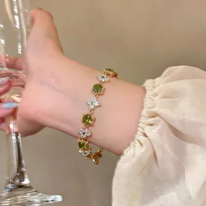 Elegant 18k gold plated bracelet with sparkling green and white cubic zirconia flowers.