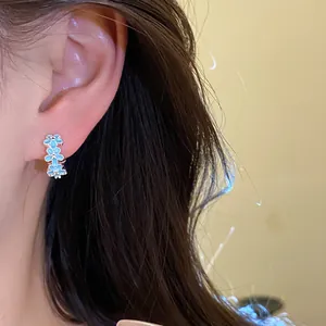 Close-up shot of light blue enamel flower hoop earrings worn by an Asian model
