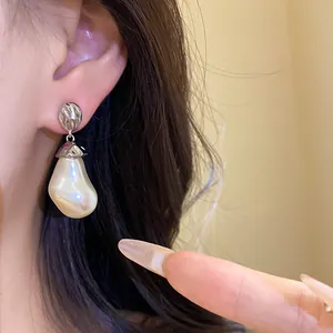 Detailed view of irregular baroque pearl drop earrings with silver wrinkled metal top