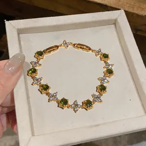 Close-up view of 18k gold plated bracelet featuring green stones and floral details