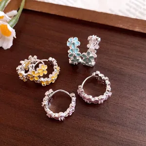 Detail of small flower huggie hoop earrings with colorful enamel oil dripping