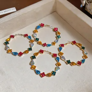 Close-up of vibrant colorful zircon hoop earrings with square and teardrop stones