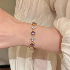 Detailed view of an 18k gold plated bracelet with purple and white zircons on a wrist