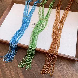 Detail view of multi-strand seed bead tassel necklaces in blue, green, and amber colors.
