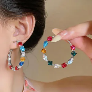 Close-up of colorful zircon hoop earrings with square and pear-shaped stones