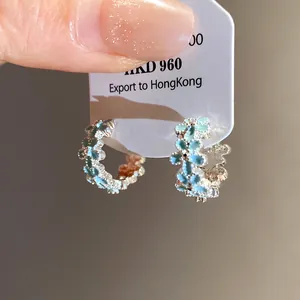 Close-up of floral drip oil hoop earrings with blue petals and light luxury design