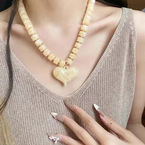 Elegante collana di perle quadrate in acrilico con pendente a cuore crema indossata