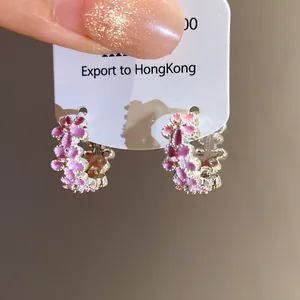 Detailed macro view of pink enamel flower hoop earrings on a white display card